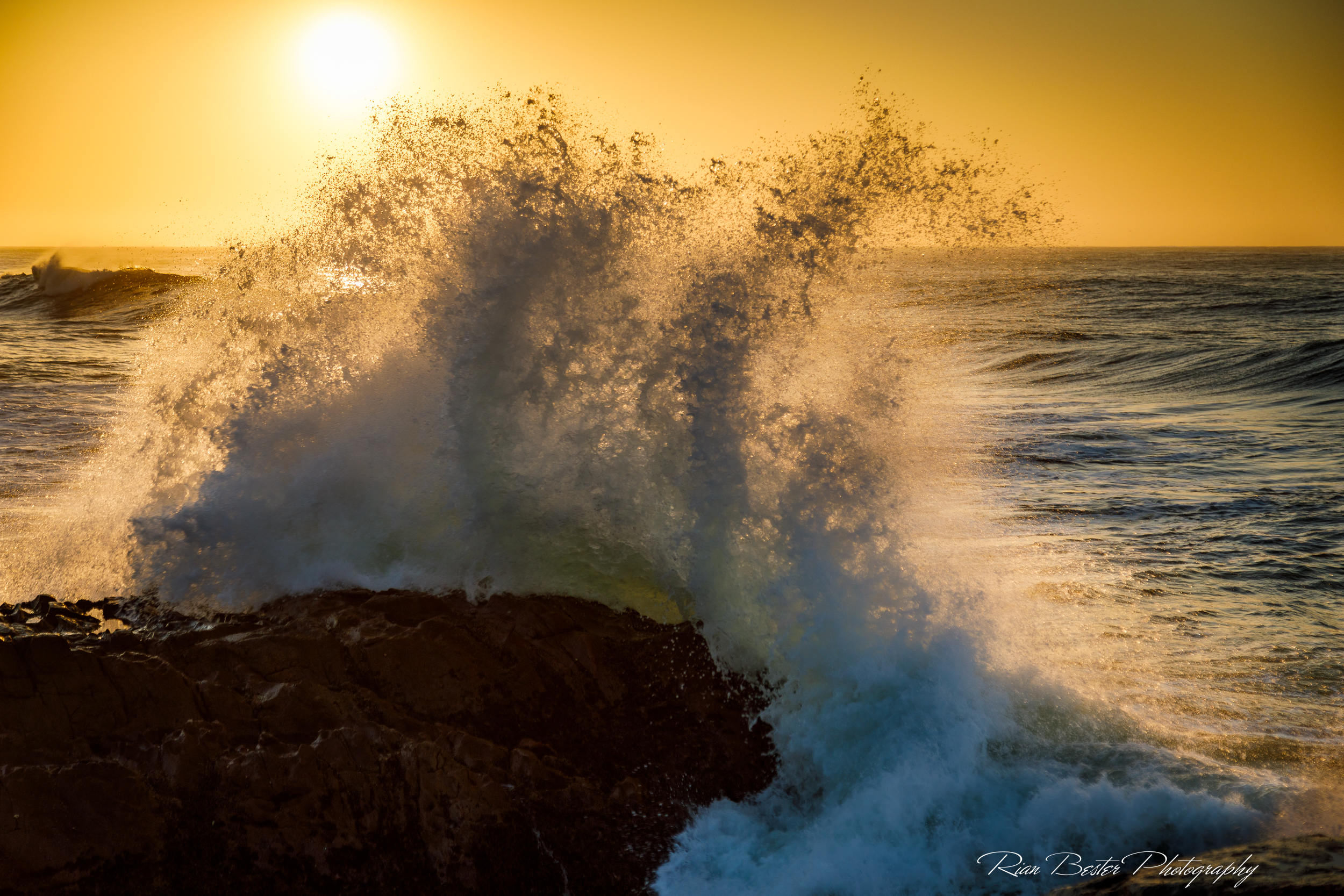 Waves crashing onto rocks at sunrise