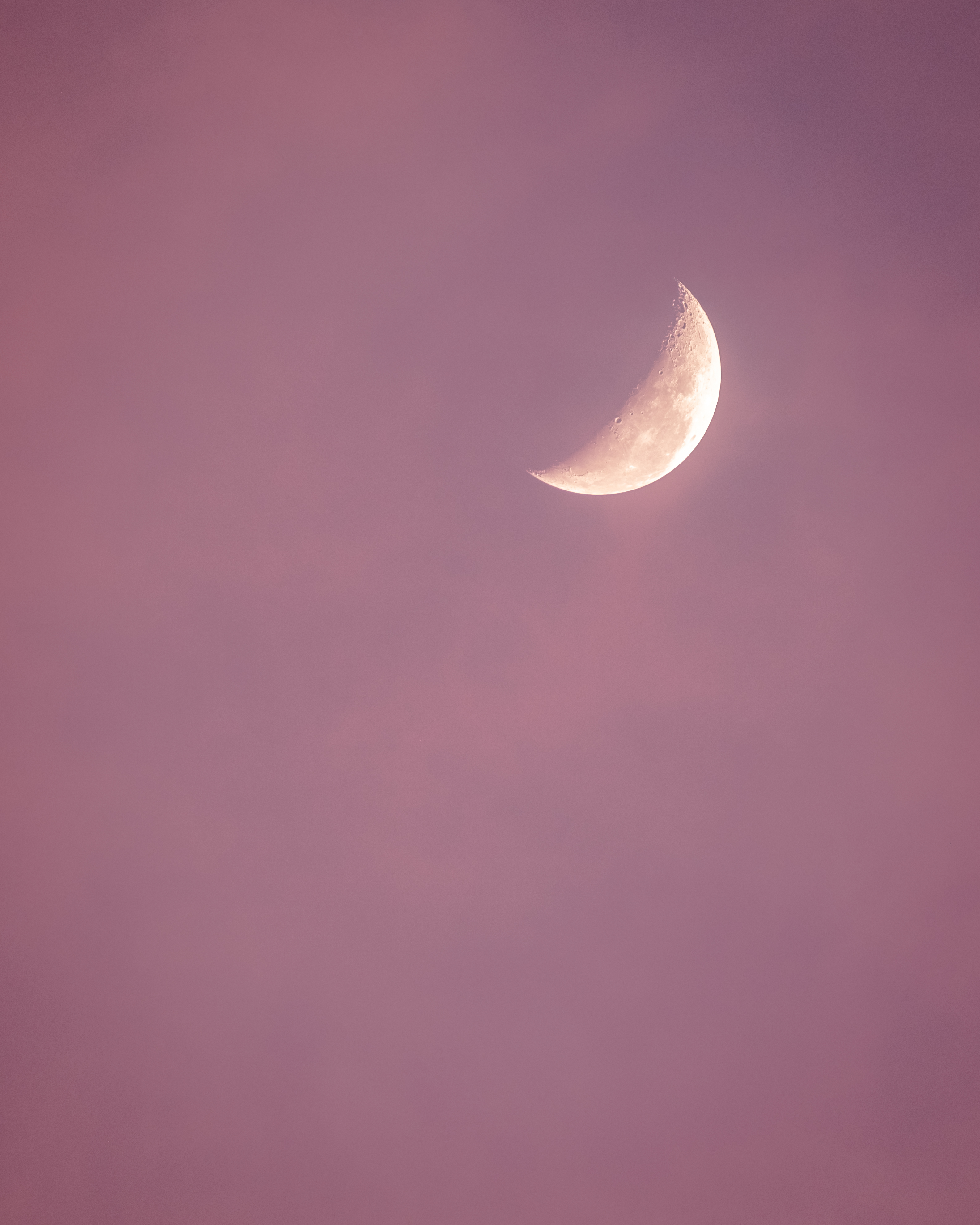 moon rising through candysloss clouds during sunrise
